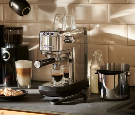Eine silberne »Lapressa« Siebträgermaschine bereitet Espresso in einem Glas zu.