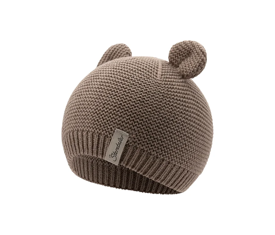 Eine hellbraune Strickmütze für Babys mit zwei kleinen, runden Ohren oben und einem 'Sterntaler'-Etikett an der Seite.
