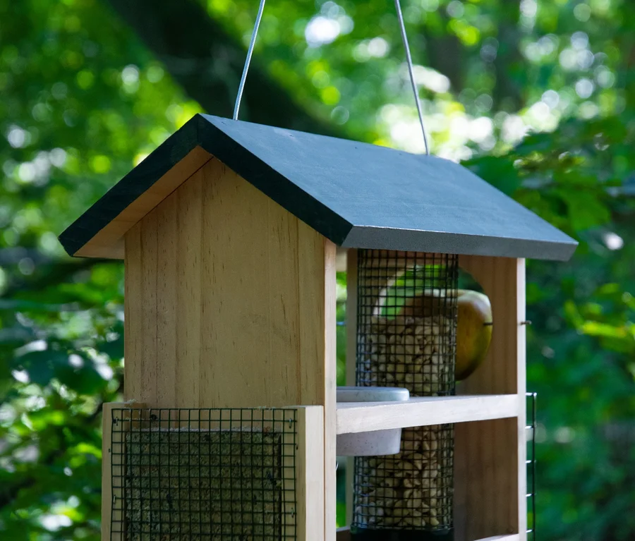 Ein hölzernes 7-in-1-Vogelhaus hängt an einem Baum.