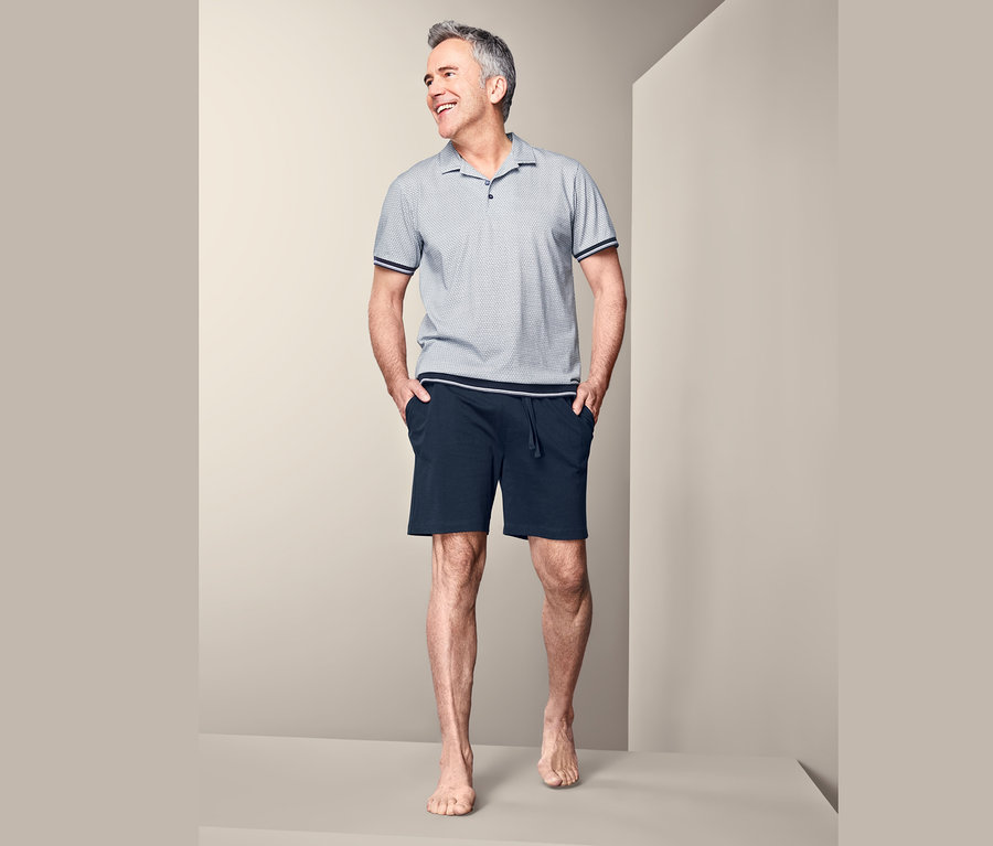 Mann steht mit Händen in den Taschen einer Shorty-Pyjama.