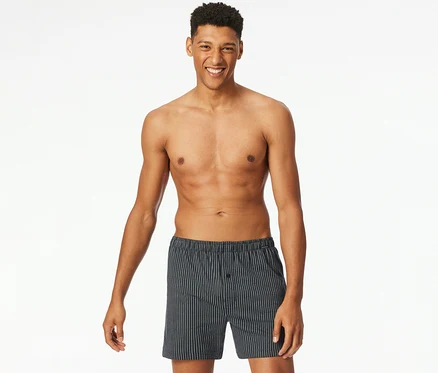 Lächelnder Mann, oberkörperfrei, trägt blau gestreifte SCHIESSER Jersey-Boxer.