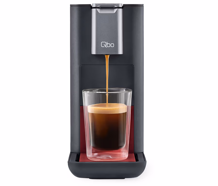 Kaffee fließt aus der Qbo ESSENTIAL Dark Berry Kaffeemaschine in ein Glas.