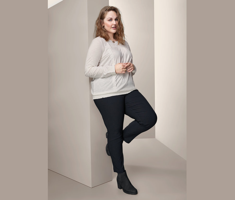 Frau posiert in Blusenshirt mit Stickerei und Bengalin-Hose.