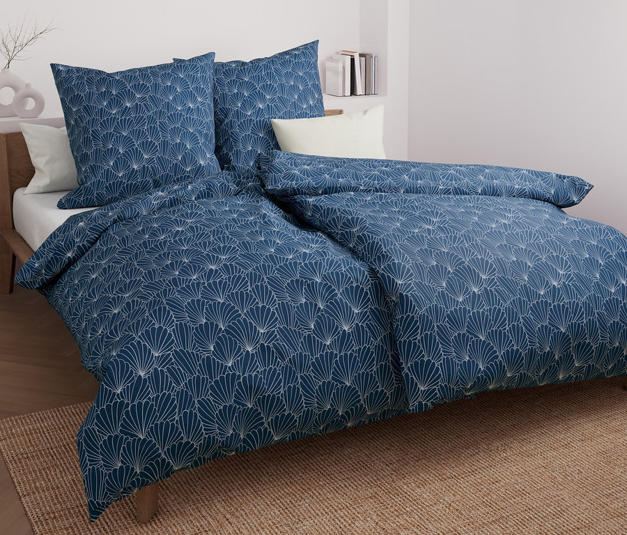 Blau gemusterte Microfaser-Bettwäsche mit Muscheln auf einem Bett.