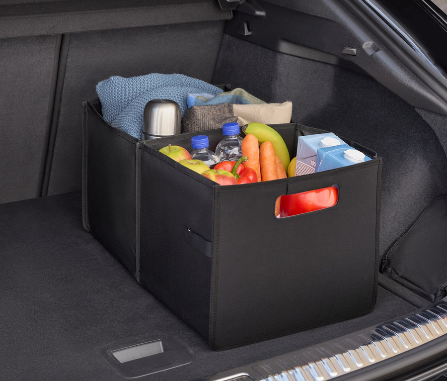 Im Kofferraum eines Autos befindet sich ein schwarzer Organizer gefüllt mit Lebensmitteln, Wasserflaschen, Obst und Gemüse.