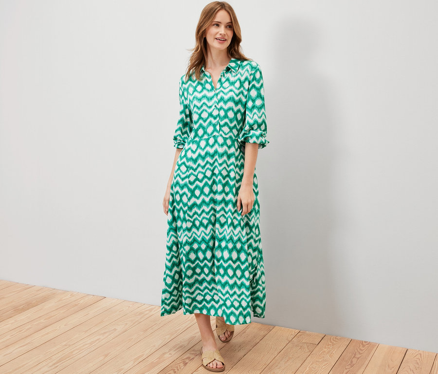 Frau posiert in einem grün bedruckten Hemdblusenkleid.
