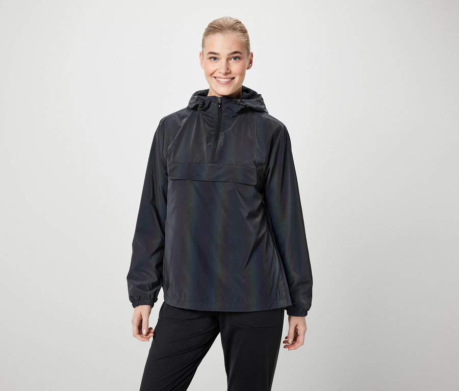 Frau trägt eine schillernde Jacke mit Kapuze und eine schwarze Hose.