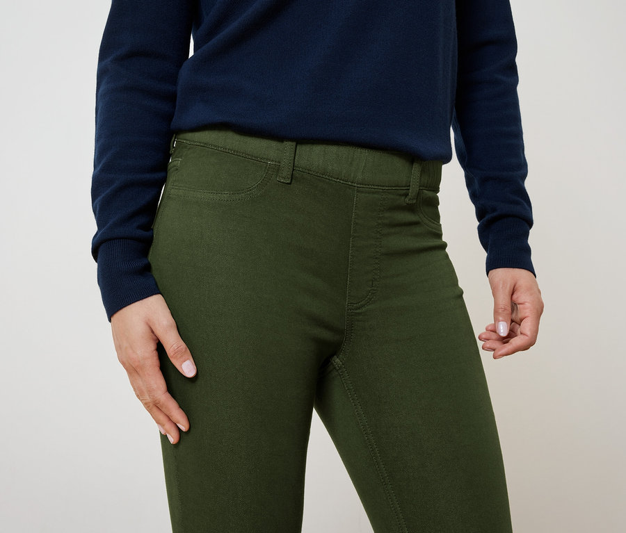 Detailaufnahme einer Frau, die olivgrüne Hosen und einen dunkelblauen Pullover trägt.