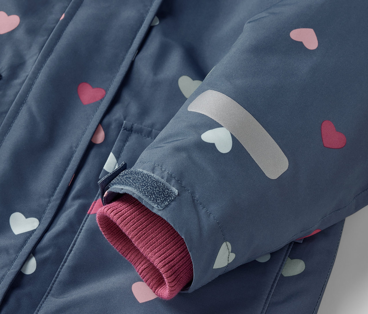 Detail einer blauen 2-teiligen Kinder-Schneekombi mit rosa und weißen Herzen.