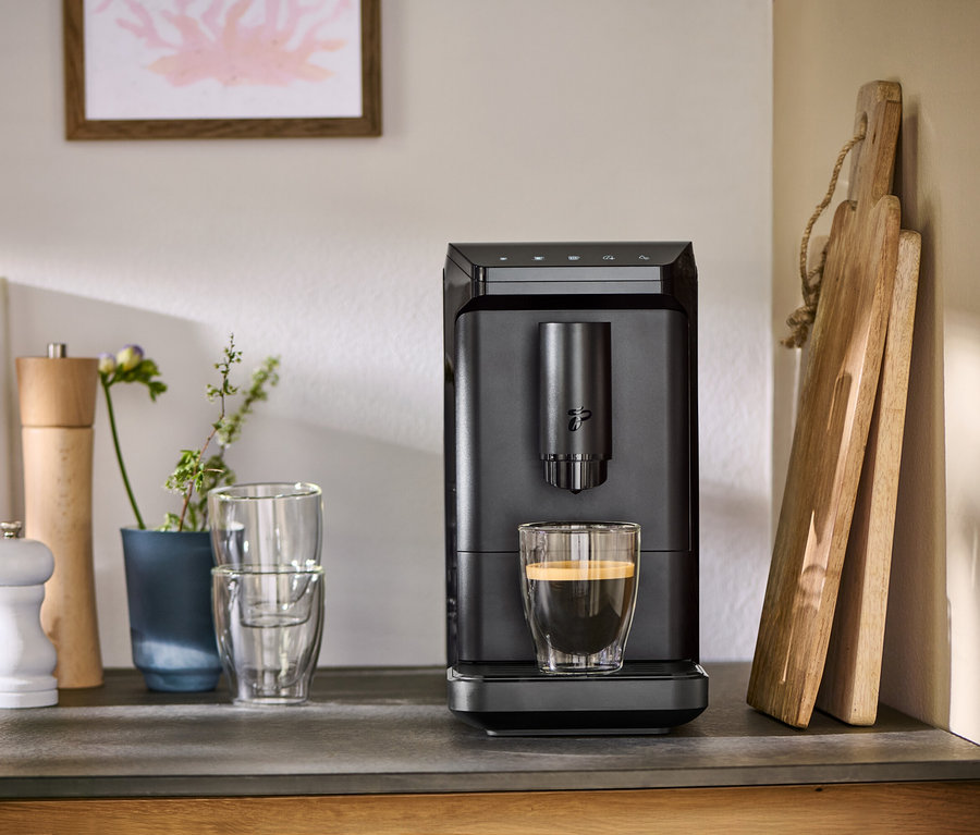 Auf einer Küchentheke steht eine schwarze »Esperto mini« und bereitet Kaffee in einem Glas zu.