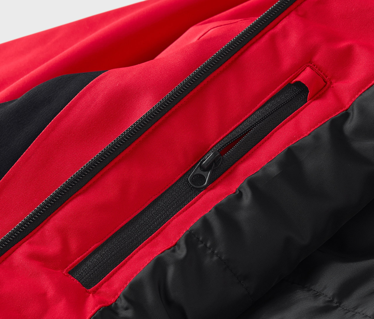 Detailaufnahme einer rot-schwarzen Jacke mit Reißverschlüssen.