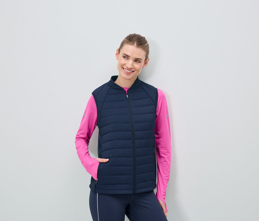 Frau trägt eine dunkelblaue Steppweste und ein pinkes Langarmshirt.