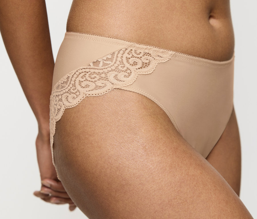 Detailaufnahme einer Frau, die einen Triumph Amourette Tai Slip in Hautfarbe mit Spitze trägt.