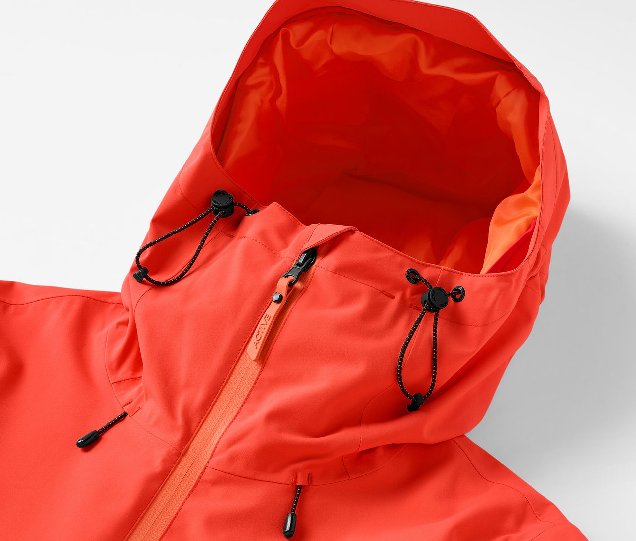 Detailaufnahme einer orangefarbenen Jacke mit Kapuze, Kordelzug und Reißverschluss.