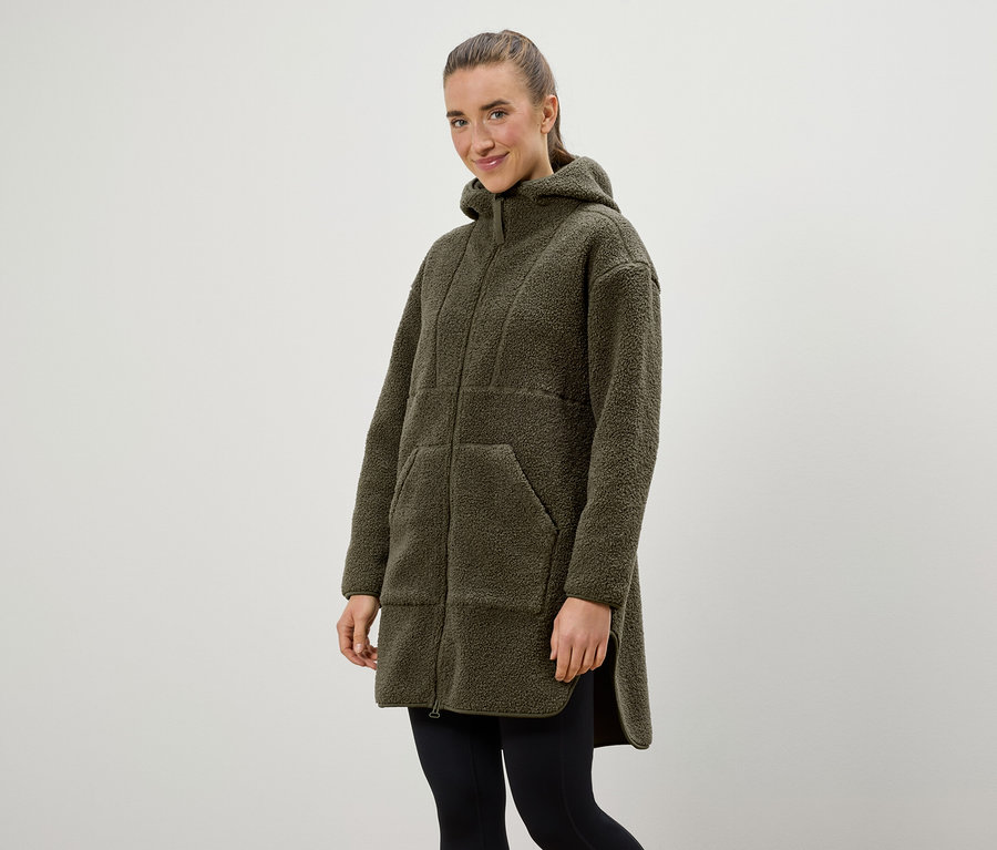 Frau trägt einen olivgrünen Kapuzenmantel und schwarze Leggings.