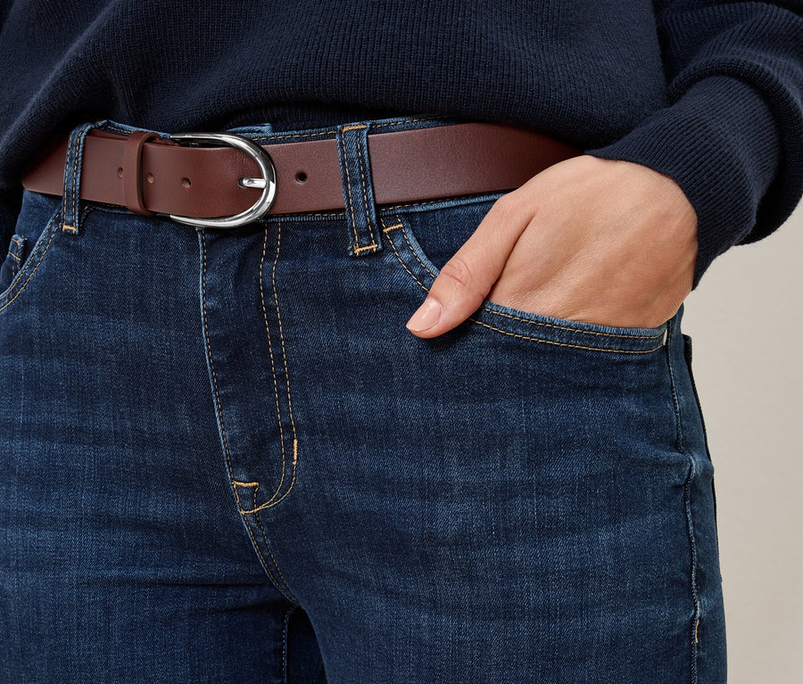 Detailaufnahme von blauen Jeans mit einem cognacfarbenen Ledergürtel.