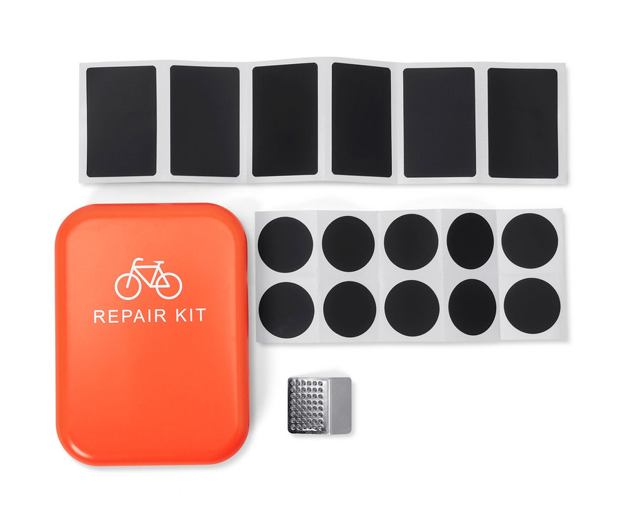 Fahrrad-Reparatur-Set mit orangefarbenem Gehäuse, Flicken und Schmirgelpapier.