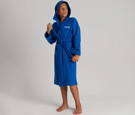 Junge trägt einen blauen arena Kinder-Bademantel Zeppelin Light JR mit Kapuze und blickt nach oben.