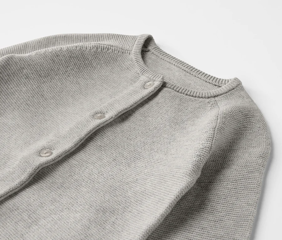 Detailansicht eines grauen Baby-Strickoveralls.