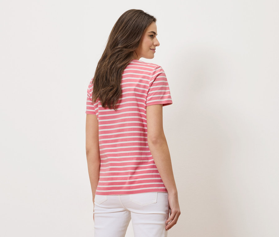 Frau von hinten, trägt ein rosa-weiß gestreiftes T-Shirt und weiße Jeans.