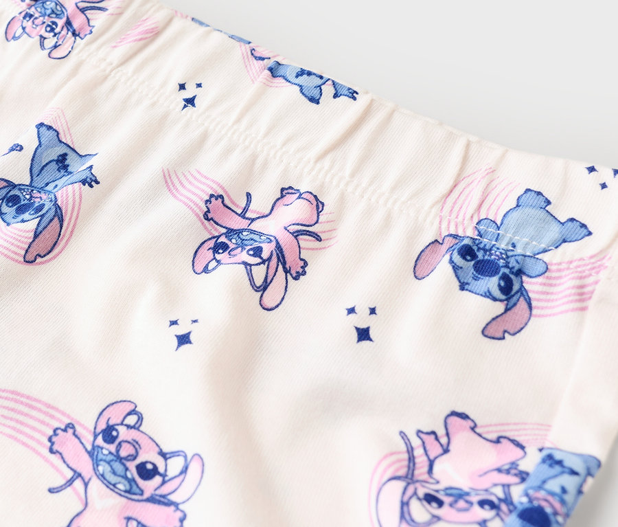 Nahaufnahme von Leggings mit Stitch-Muster in Blau und Pink auf beigem Stoff.