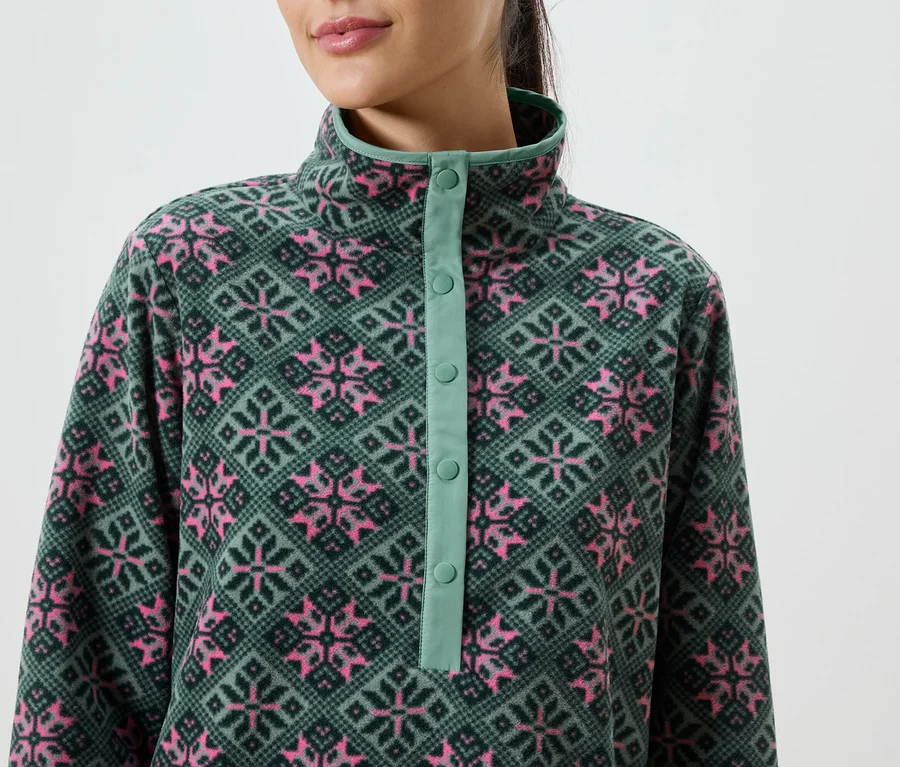 Nahaufnahme einer Frau mit einem grünen Fleece-Pullover mit rosa Schneeflocken und einer Knopfleiste.
