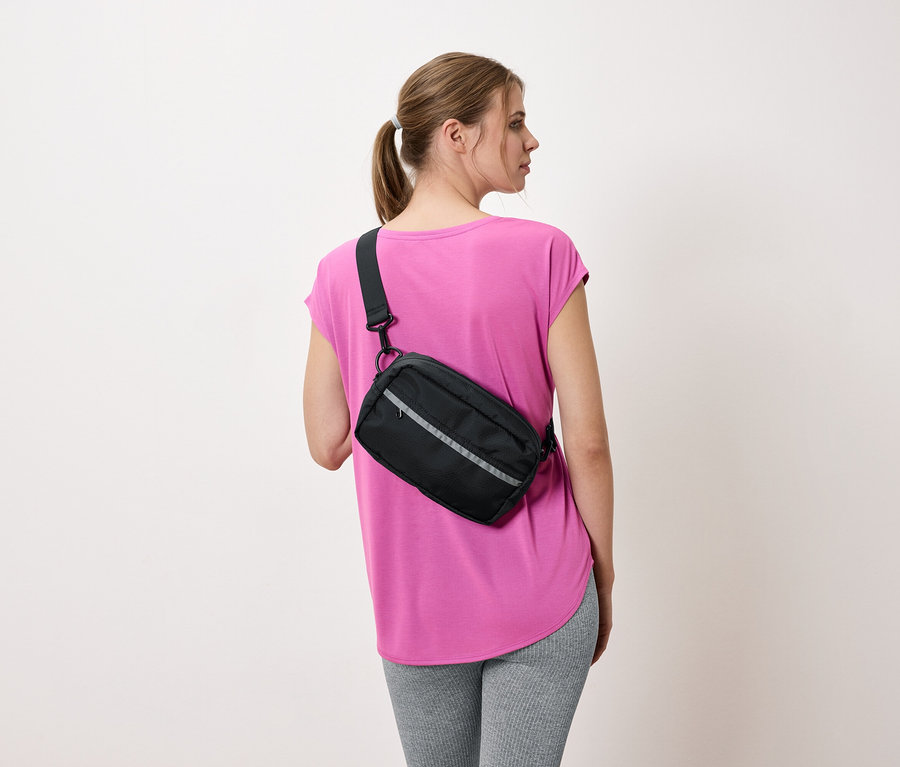 Frau von hinten mit schwarzer Umhängetasche, pinkem T-Shirt und grauer Leggings.