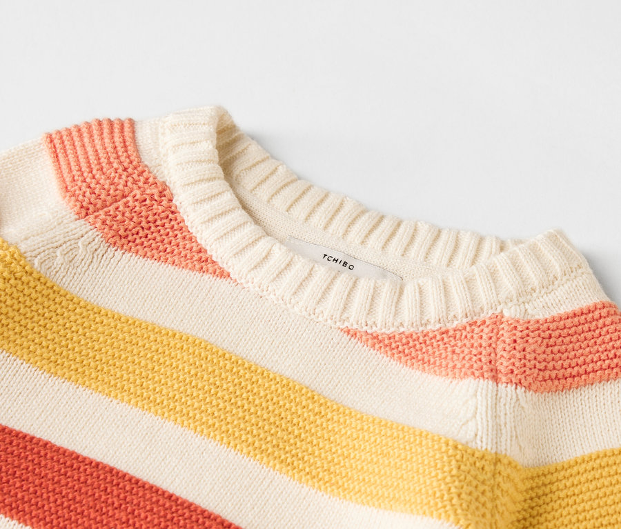 Nahaufnahme eines gestreiften Pullovers in Gelb, Rosa und Beige.