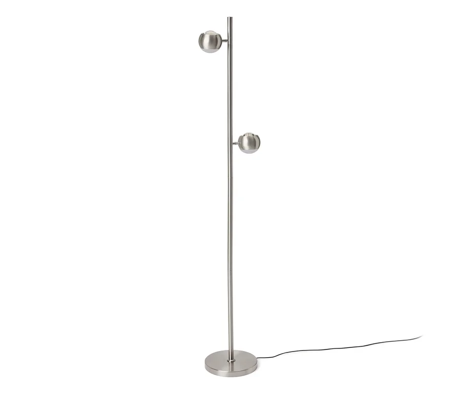 Silberne Stehlampe mit rundem Fuß und zwei kugelförmigen Leuchten an einem hohen Stab. Ein schwarzes Stromkabel liegt am Boden.