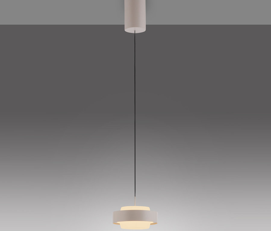 Eine moderne, helle Pendelleuchte hängt von der Decke. Sie hat eine zylindrische Deckenhalterung, ein dünnes schwarzes Kabel und eine geschichtete, scheibenförmige Lampe, die warmes Licht abgibt.