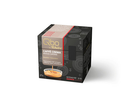 Schwarze, würfelförmige Qbo by Tchibo Kaffeekapselbox. Auf der Vorderseite steht der Produktname 'CAFFÈ CREMA MENOS CAFEÍNA', die Herkunft 'Brasilien | Kolumbien' und die Beschreibung 'Harmonisch-mild mit leicht süßlicher Note | entkoffeiniert'. Zudem sind '27x' und die 'INTENSITÄT 5/10' angegeben. Ein Bild zeigt Kaffee in einer Tasse.