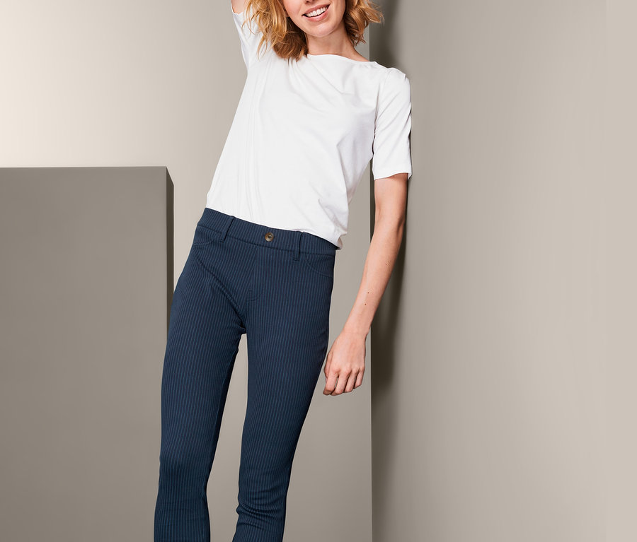 Frau posiert in Jeggings, weißem T-Shirt und braunen Stiefeln.