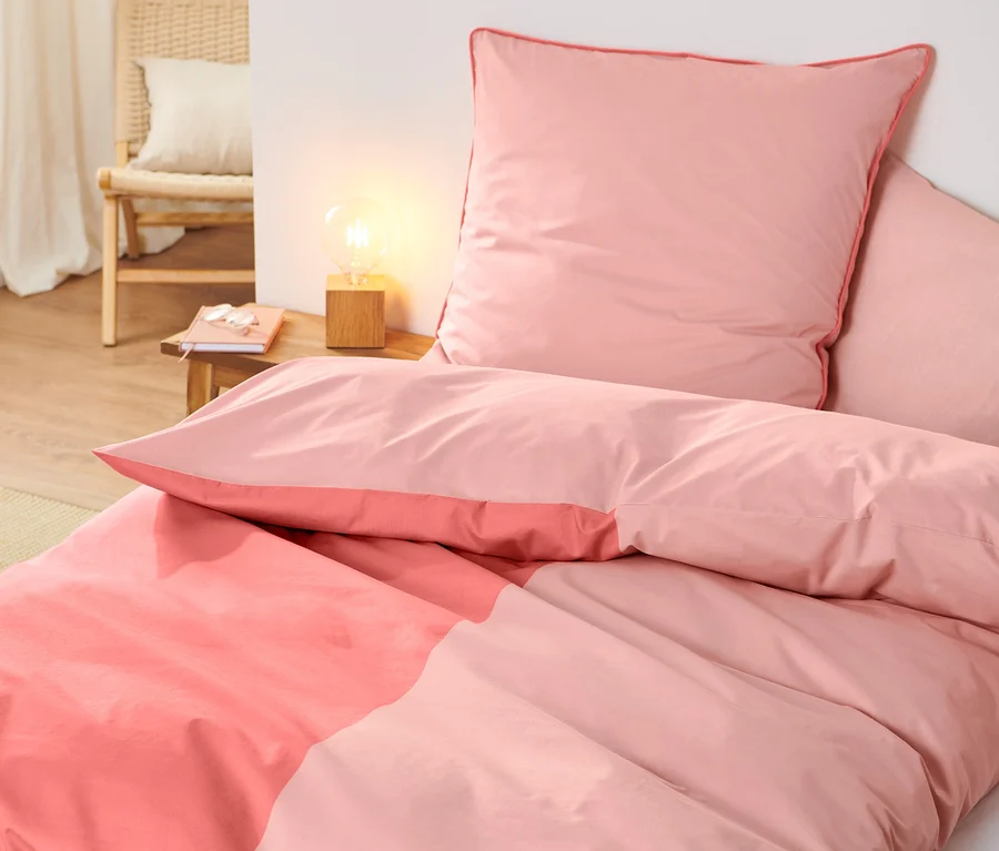 Rosa Premium-Baumwoll-Bettwäsche in Normalgröße und Übergröße auf einem Bett.