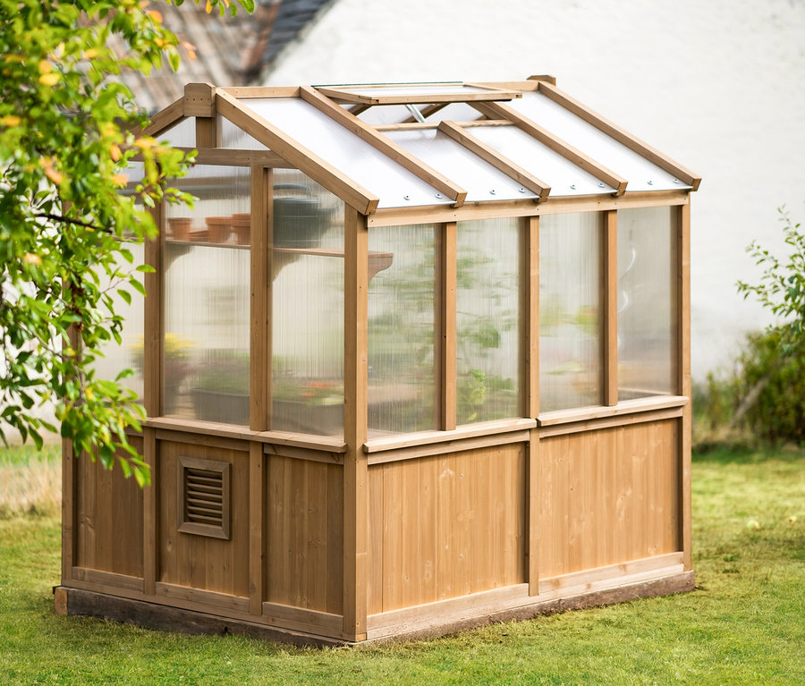 Kleines Gewächshaus aus Zedernholz steht auf einer Rasenfläche.