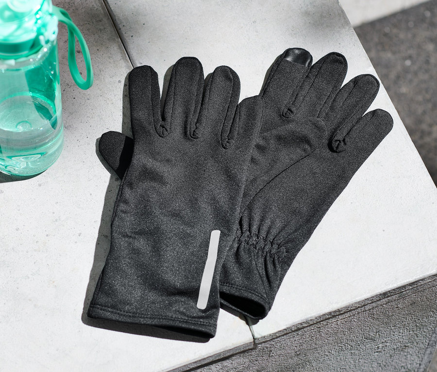 Auf einer Betonfläche liegen Laufhandschuhe und eine Wasserflasche.