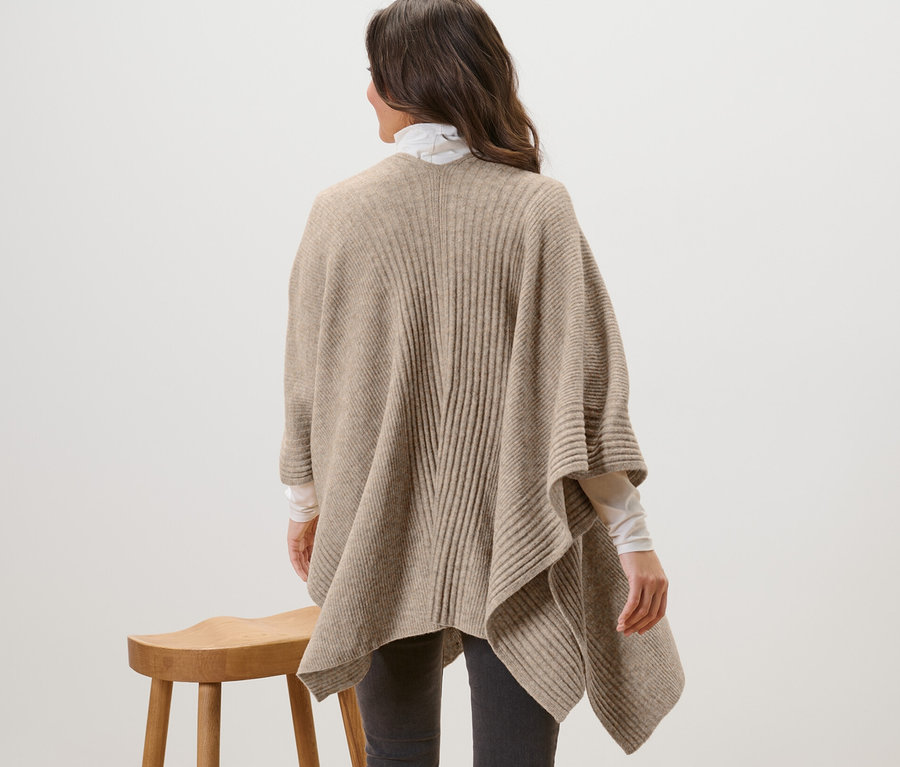 Frau von hinten trägt ein Strick-Cape.