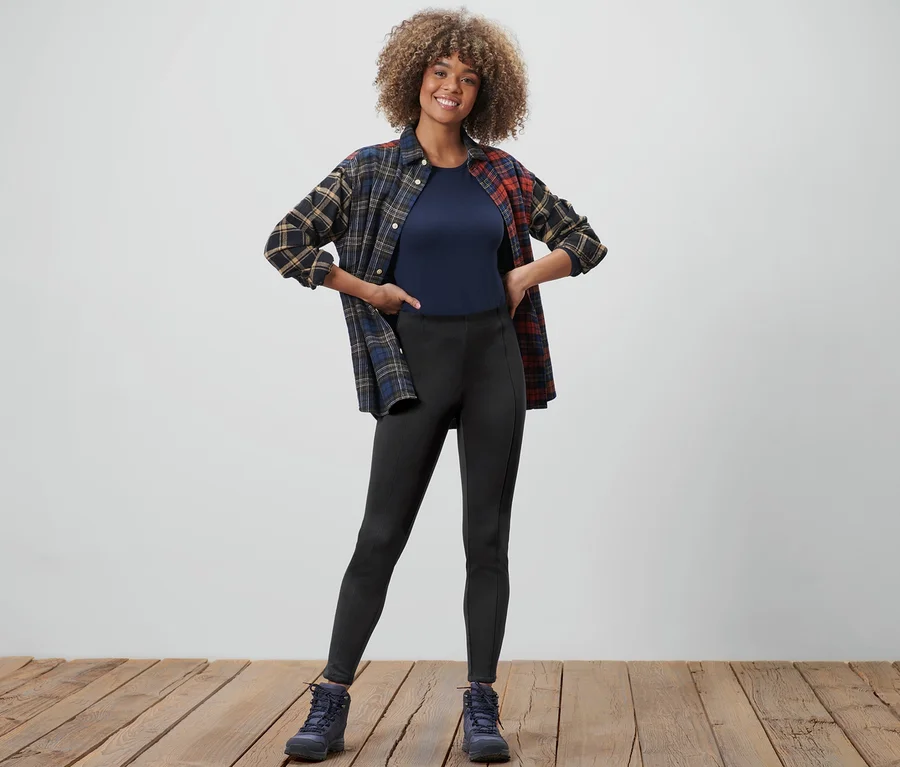 Frau posiert in Thermotights, T-Shirt und Flanellhemd.