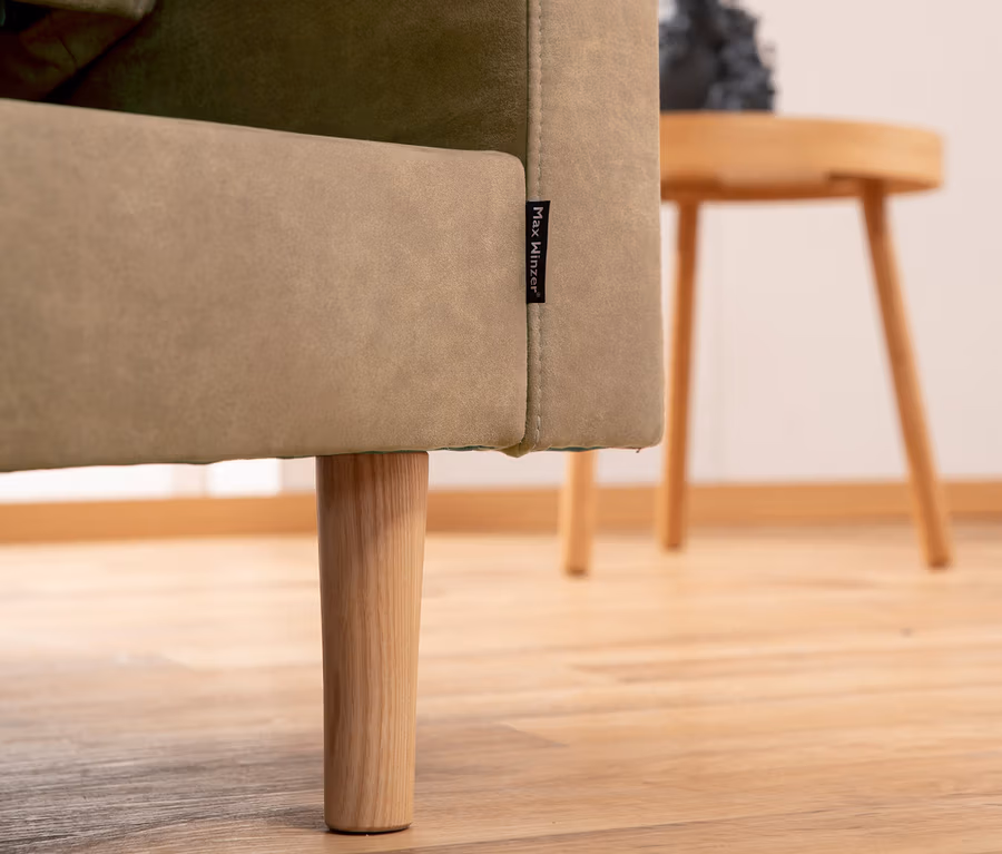 Detailaufnahme Ecke Federkern-Eckschlafsofa »Just More« mit Stauraumbank, Sahara, mit Holzfuß und kleinem Holztisch im Hintergrund.