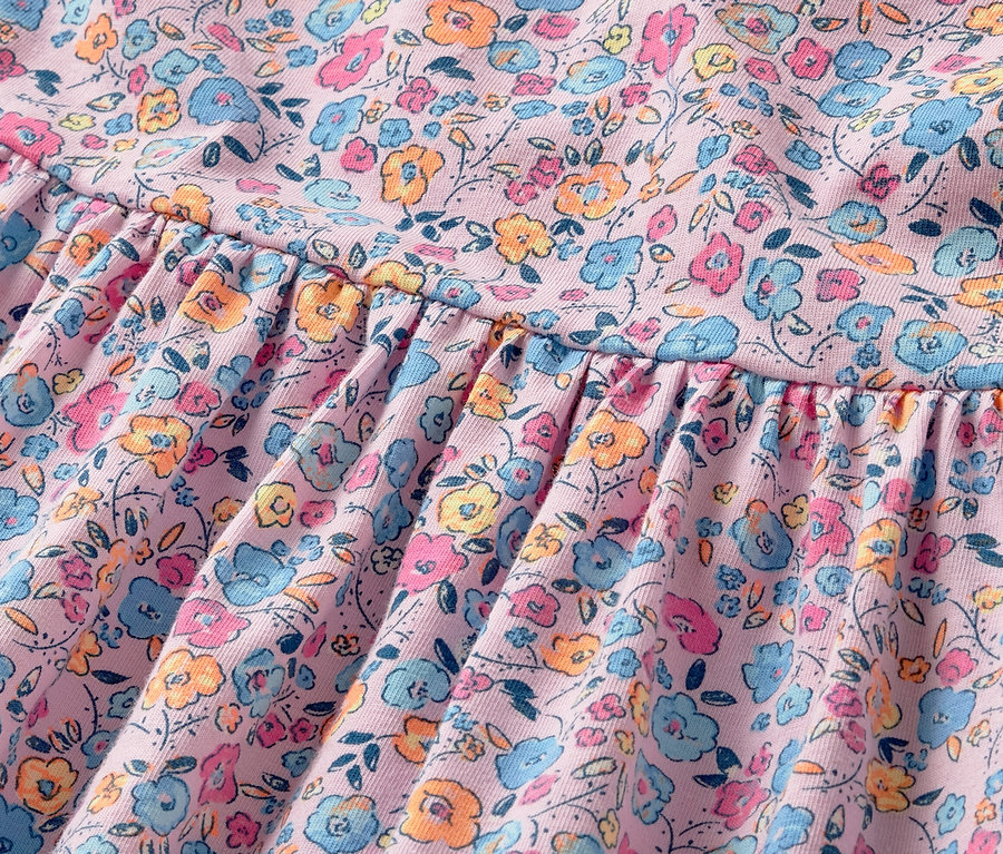 Detailansicht eines Kinder-Jerseykleids mit Blumenmuster.