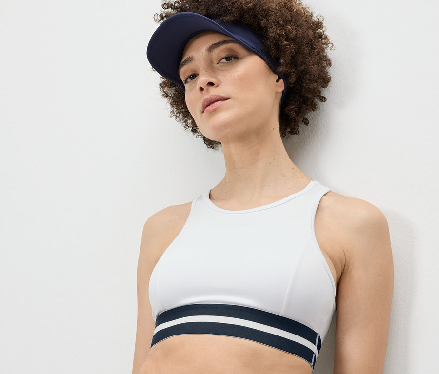 Frau trägt ein weißes Sport-Bustier »Crop Top« und einen blauen Schirm.