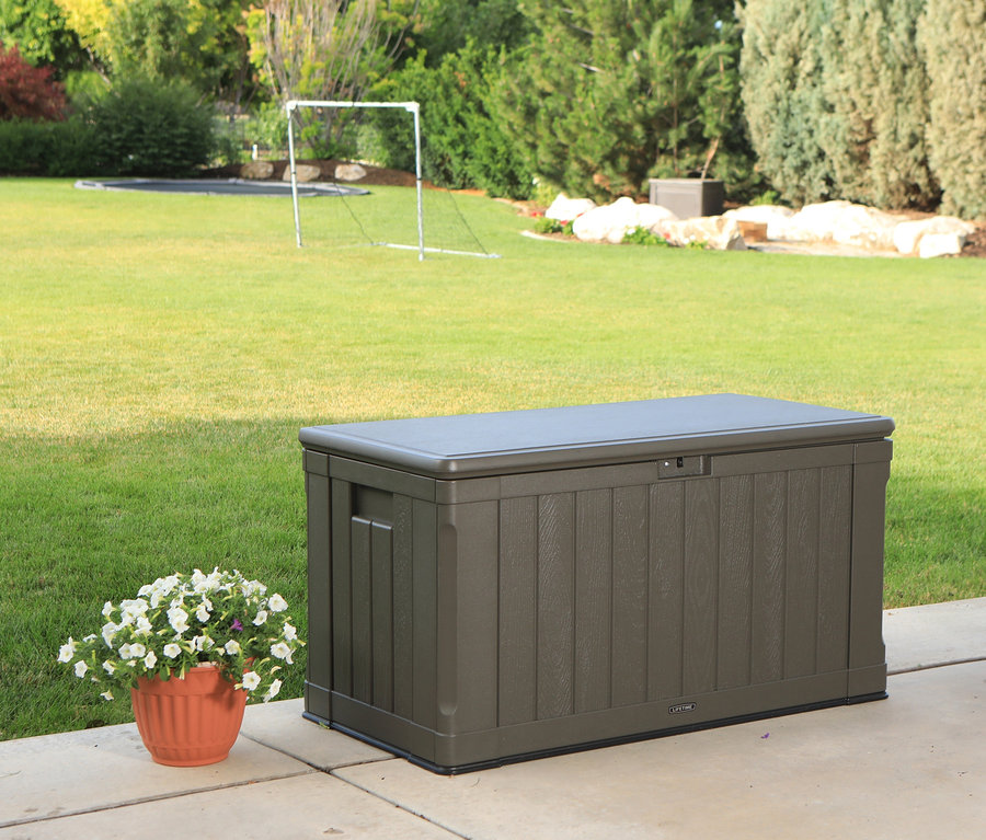 Eine braune Lifetime-Kissenbox mit einem Blumentopf auf einer Terrasse.