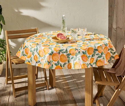 Abwischbare, runde Tischdecke mit Zitrusdruck auf einem Tisch mit Gläsern und Obst.