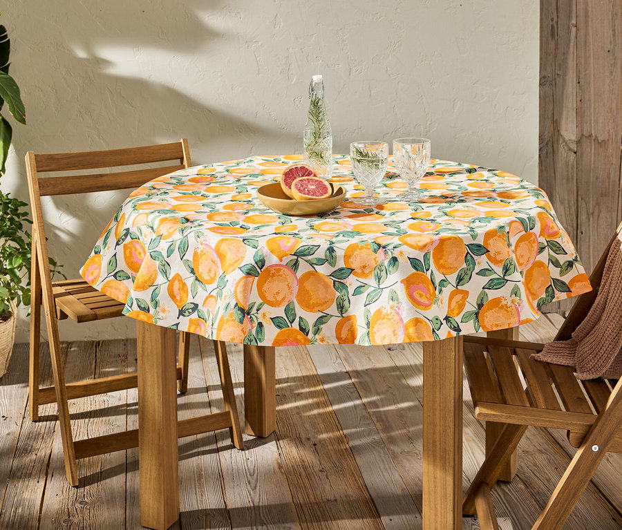 Abwischbare, runde Tischdecke mit Zitrusdruck auf einem Tisch mit Gläsern und Obst.