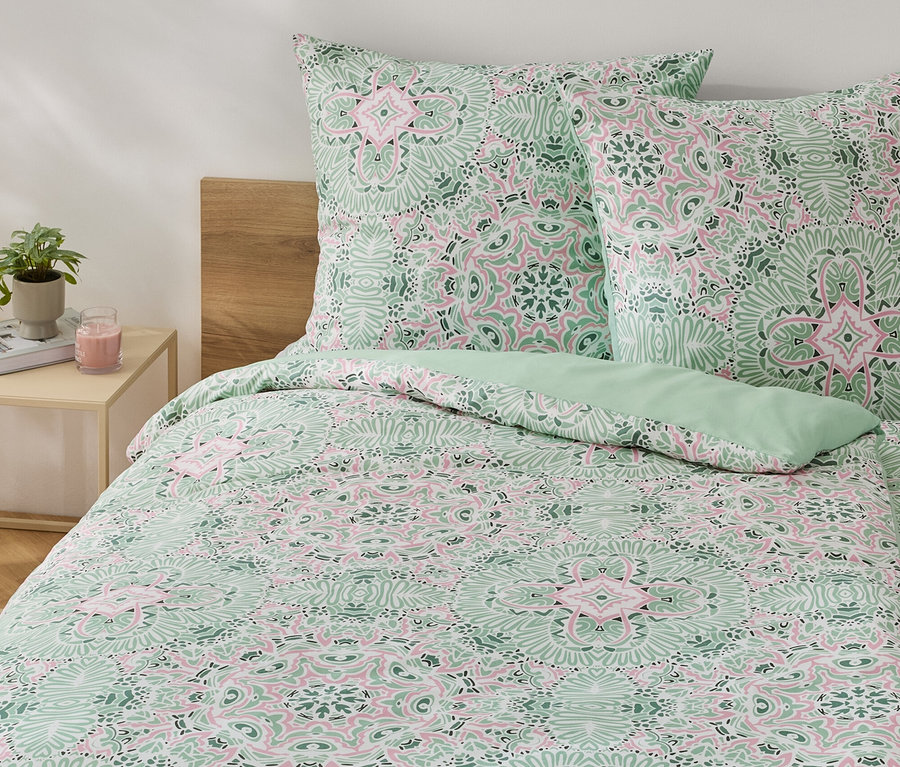 Grüne Microfaser-Bettwäsche in Normalgröße mit Blumenmuster auf einem Bett.