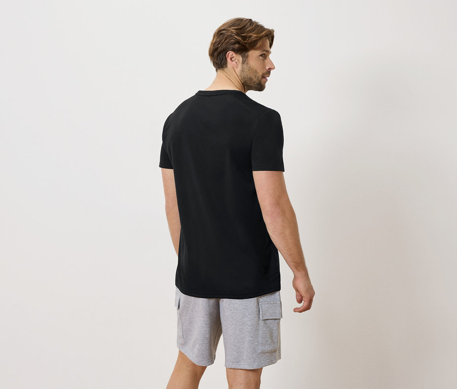 Mann von hinten in schwarzem T-Shirt und grauen Shorts
