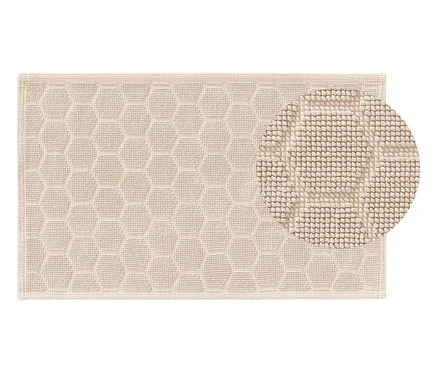 Beige Badematte mit sechseckigem Muster und Detailaufnahme der Textur.