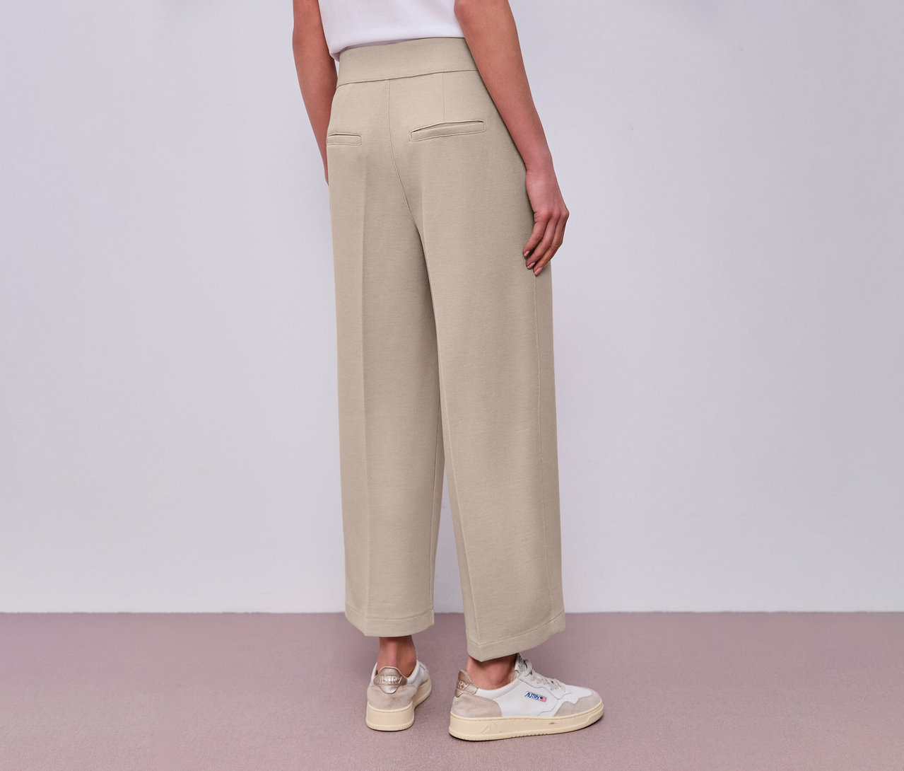 Rückansicht einer Frau mit Street One 7/8-Culotte in Beige und weißen Turnschuhen.
