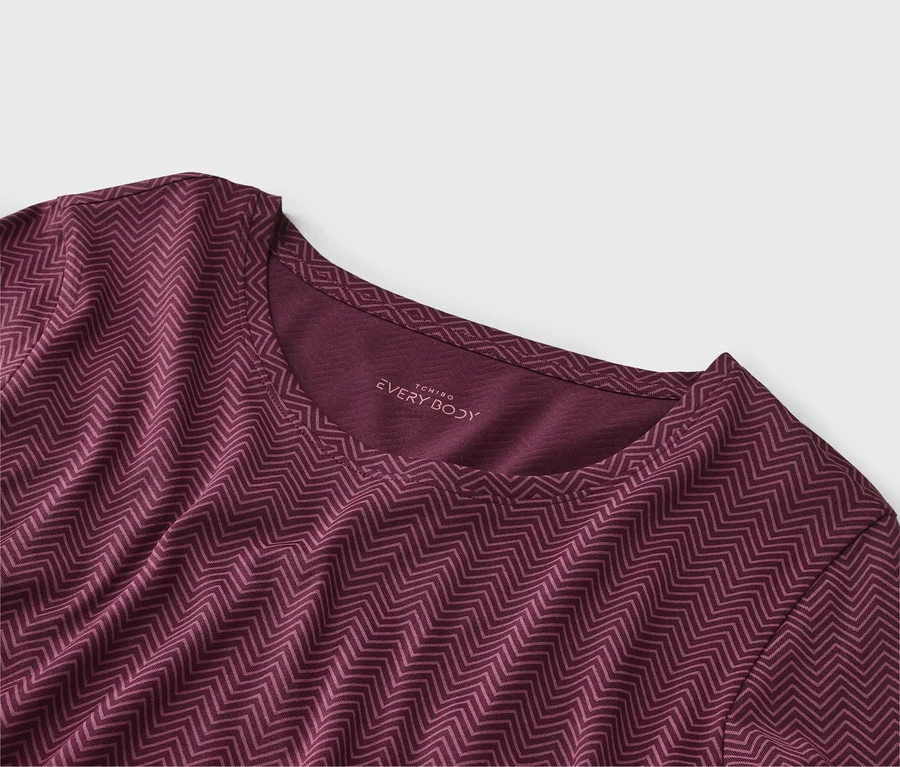 Nahaufnahme eines weinroten T-Shirts mit Zickzackmuster und "EVERY BODY"-Schriftzug am Halsausschnitt.