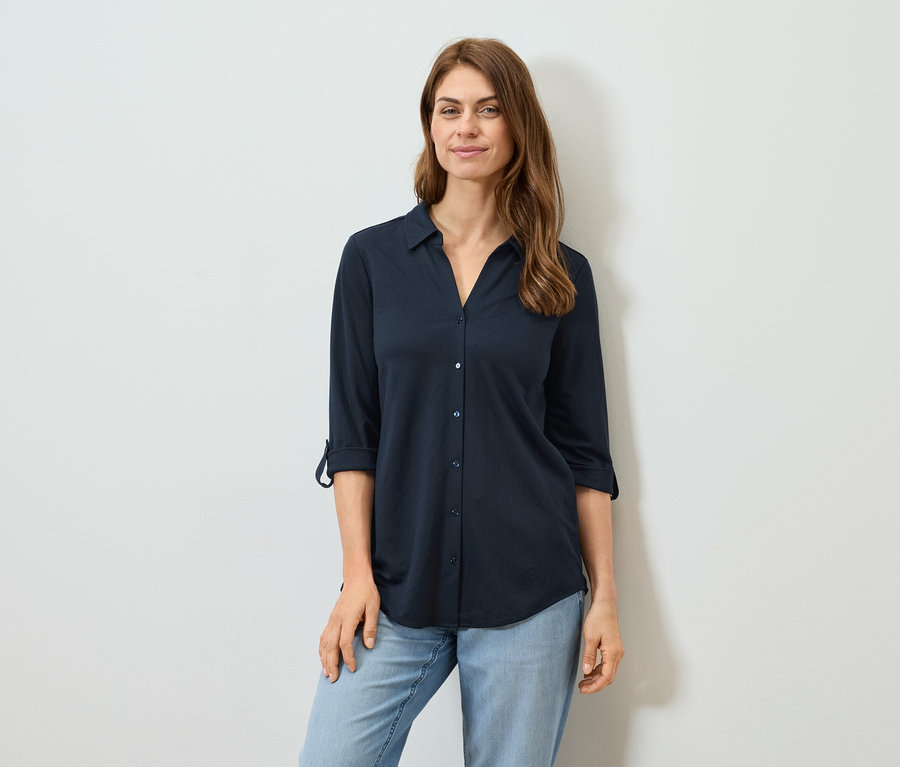 Frau trägt ein marineblaues Langarmhemd und Jeans.