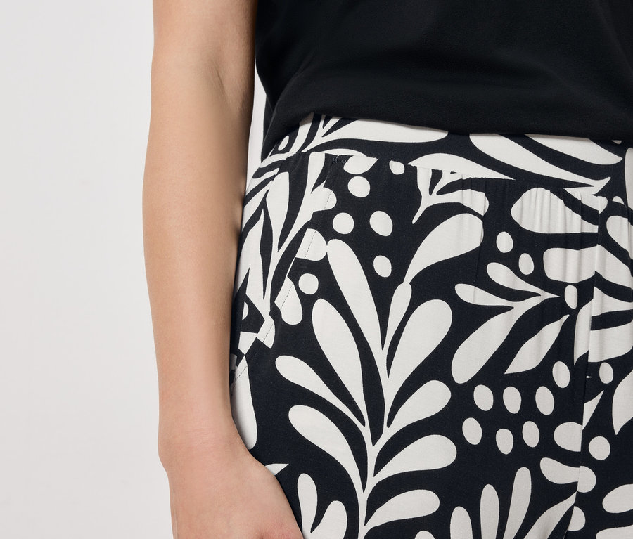 Nahaufnahme einer Frau, die ein schwarz-weiß gemustertes Kleid trägt.